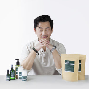 A photo of Kevan Kwok, founder of Aether Health with the full range of Aether Health natural skincare products.