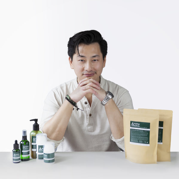 Load image into Gallery viewer, A photo of Kevan Kwok, founder of Aether Health with the full range of Aether Health natural skincare products.