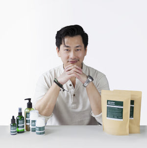 A photo of Kevan Kwok, founder of Aether Health with the full range of Aether Health natural skincare products. 