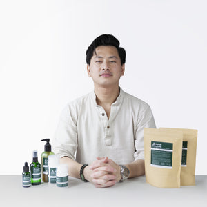 A photo of Kevan Kwok, founder of Aether Health with the full range of Aether Health natural skincare products.